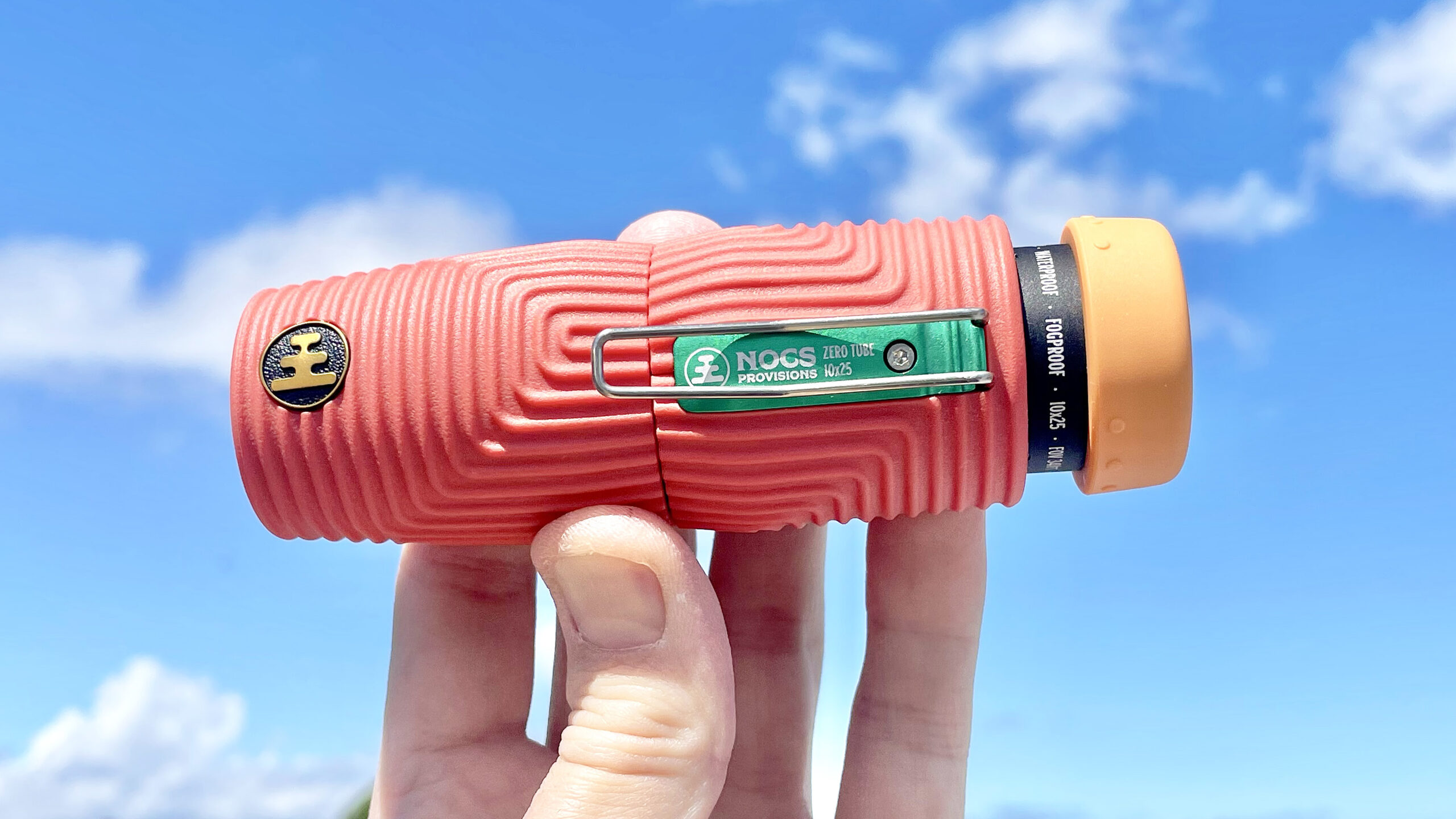 Nocs Zero Tube rugged monocular in orange shown close-up in a user's hand