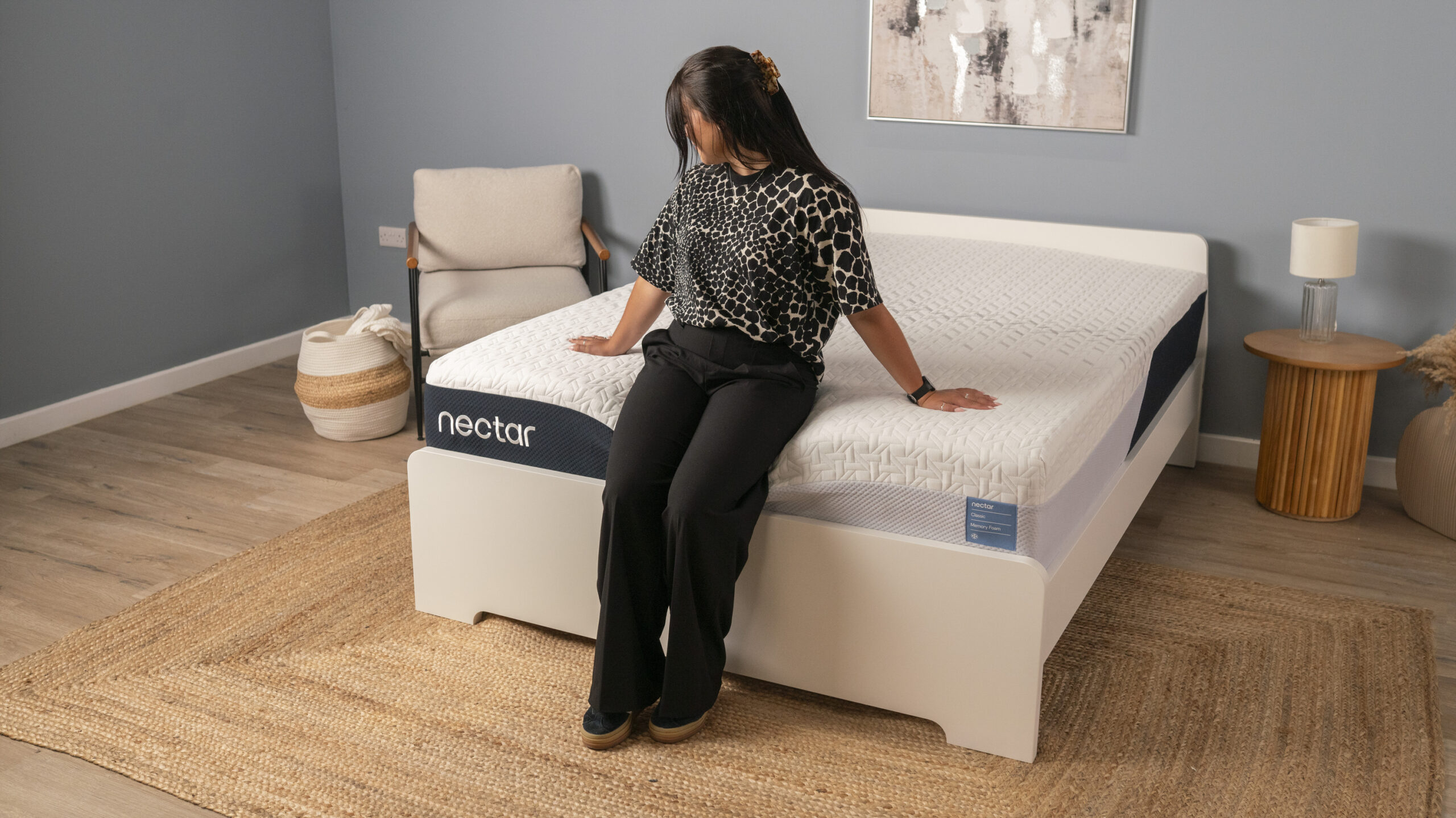A Tom's Guide sleep writer sitting on the edge of the Nectar Classic in a clean, minimalist sleep studio