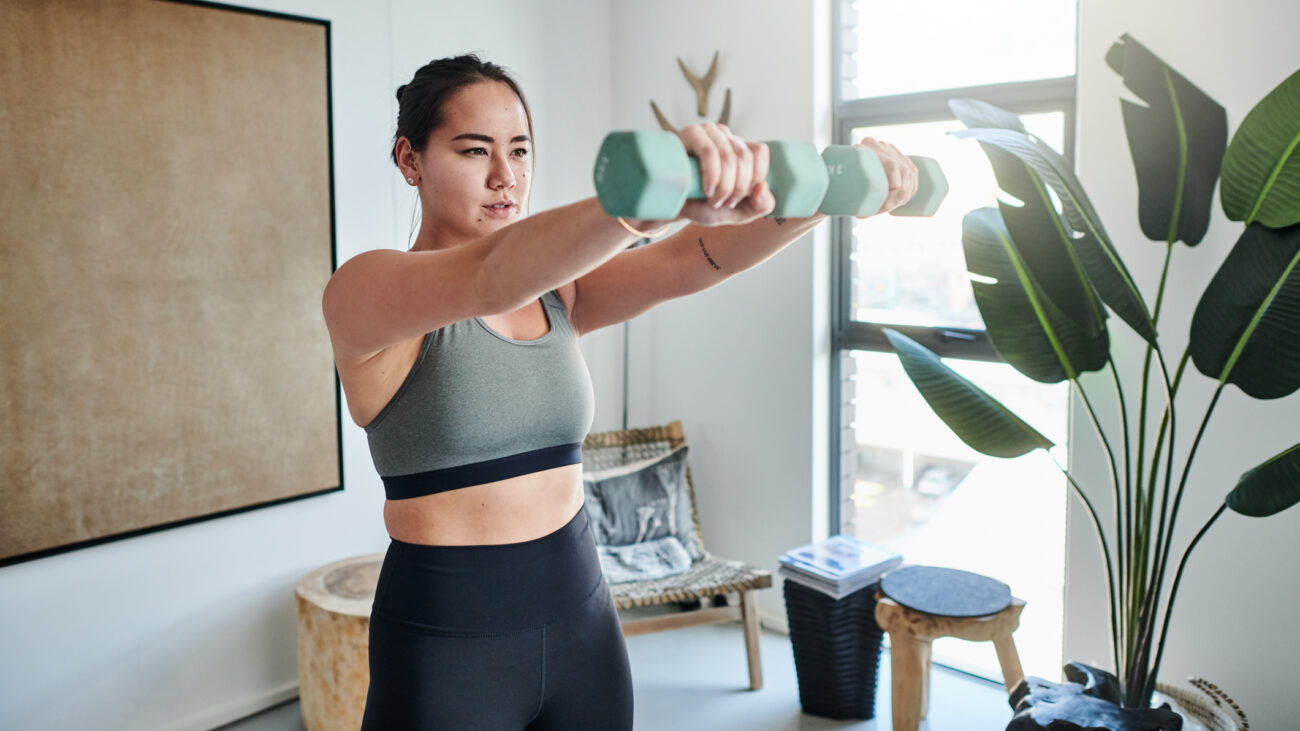 Woman exercising with dumbbells at home