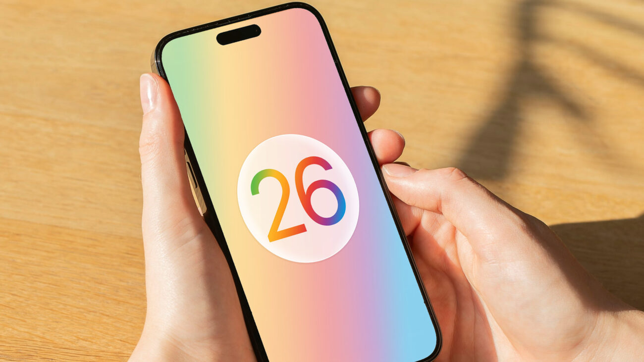 A render of the Apple iOS 26 logo on an iPhone held in a hand.