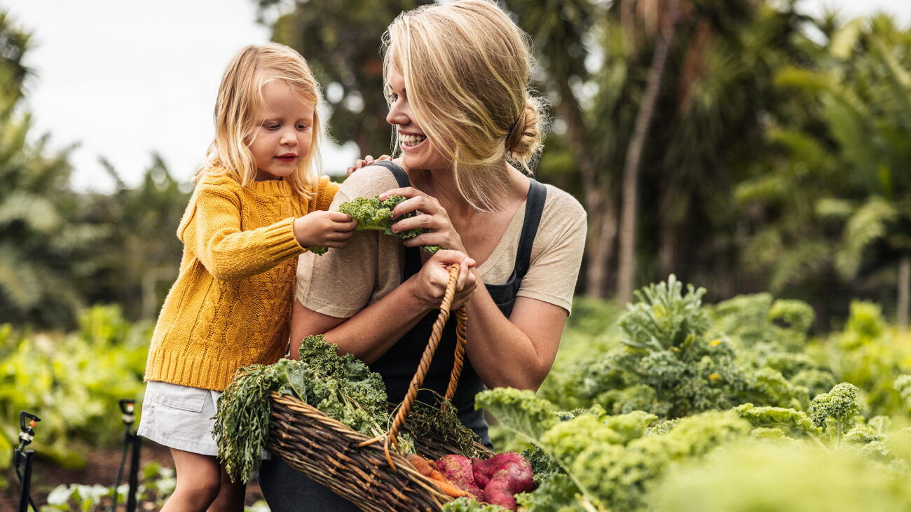 Happy mom picking fresh vegetables with her daughter