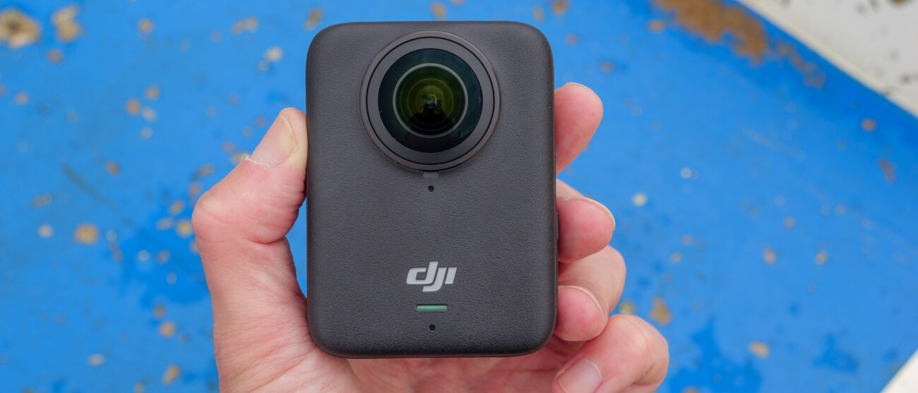 DJI Osmo 360 camera in hand with blue background