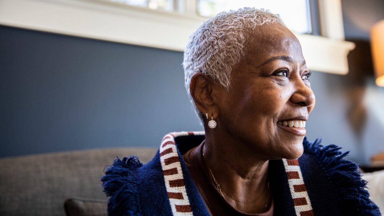 older woman looking sideways to the camera with a smiling happy face.