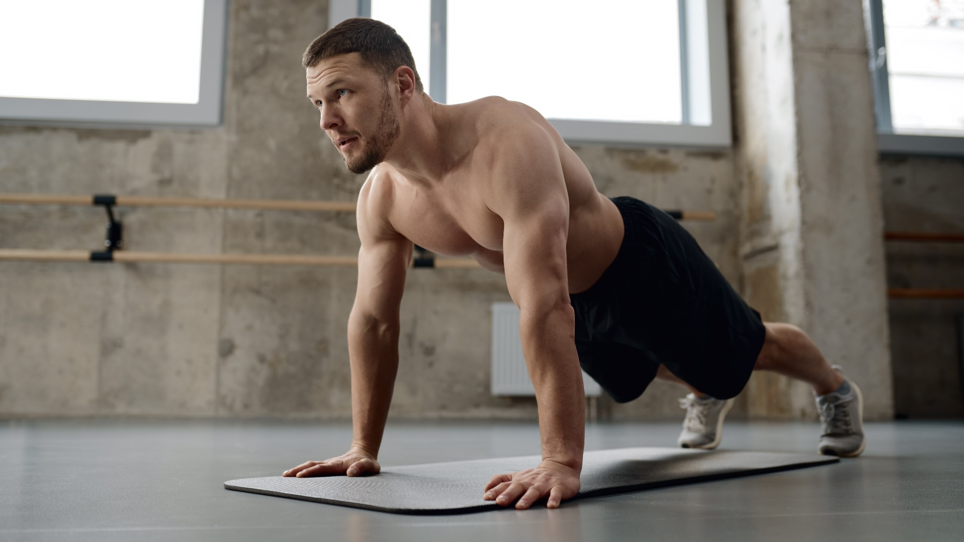 Young athletic man doing push-ups physical workout in gym
