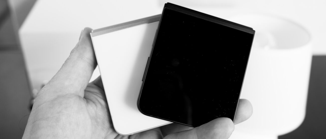 Two Samsung Galaxy Z Flip 7 FE devices in black and white closed in hand