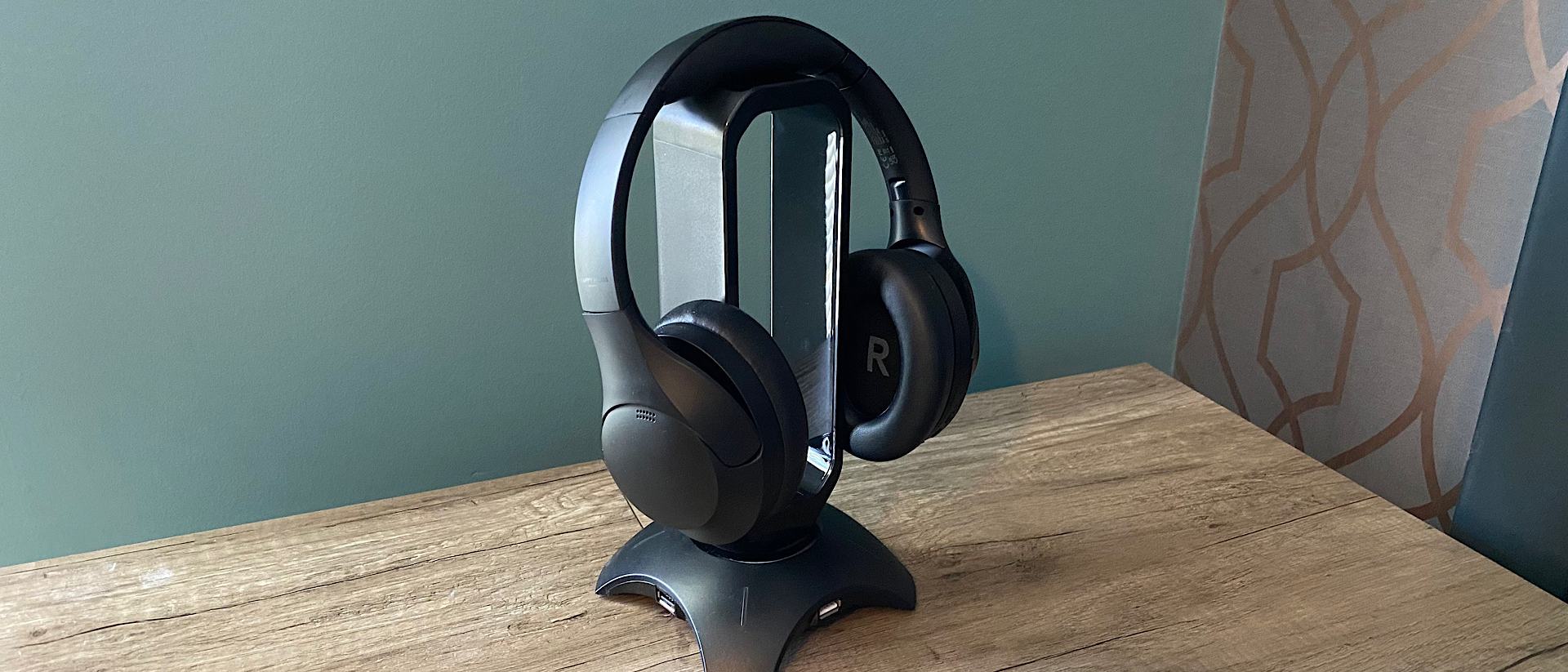 Happy Plugs Play Pro over-ear headphones hanging on a stand, on a wooden table