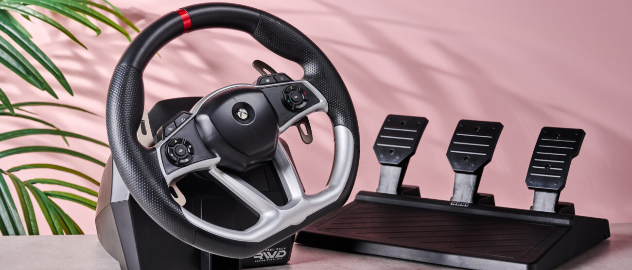 Hori Force Feedback Racing Wheel DLX on desk with plant and pink wall in background