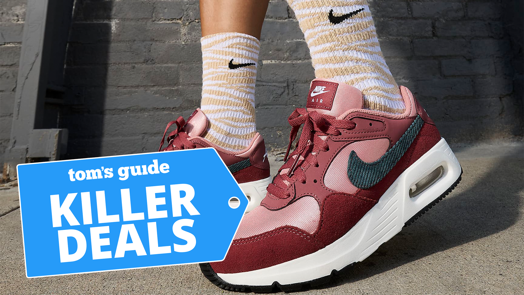 woman wearing Nike Air Max SC SE in red in front of brick building with mid-calf socks on