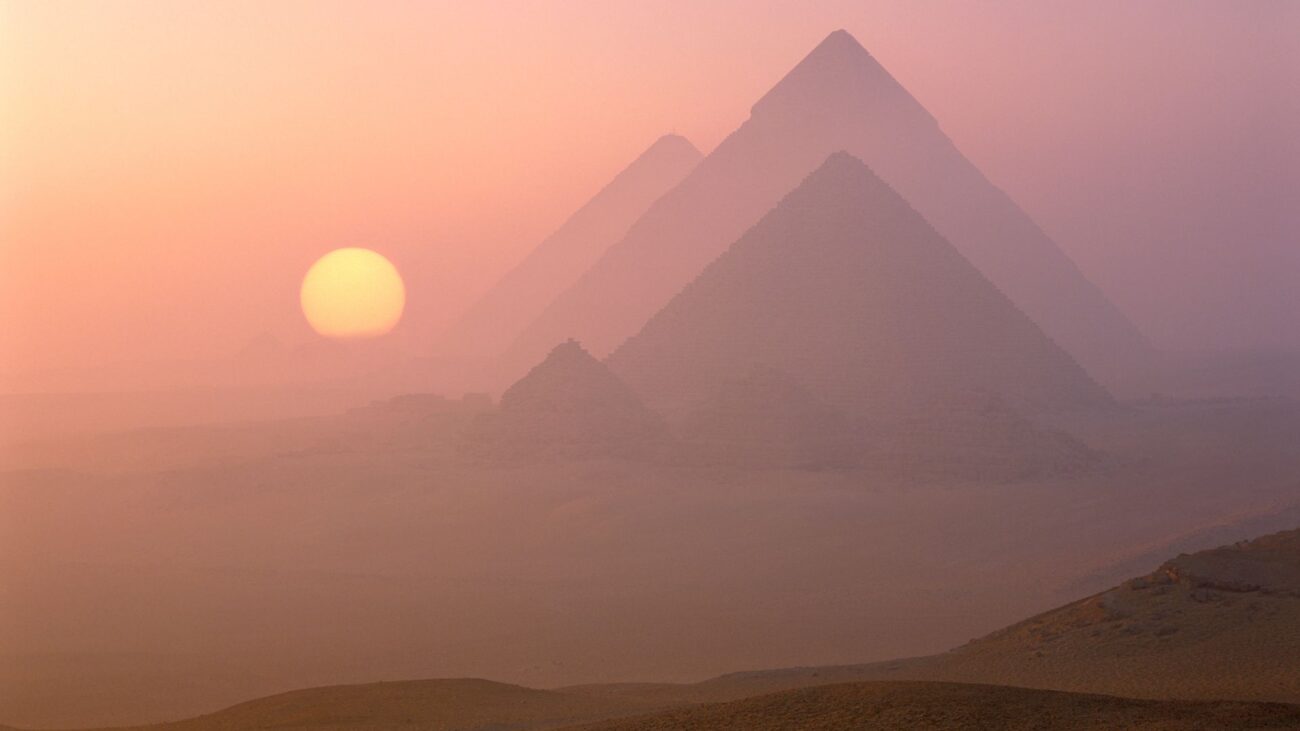 An Egyptian landscape showing pyramids and a setting sun