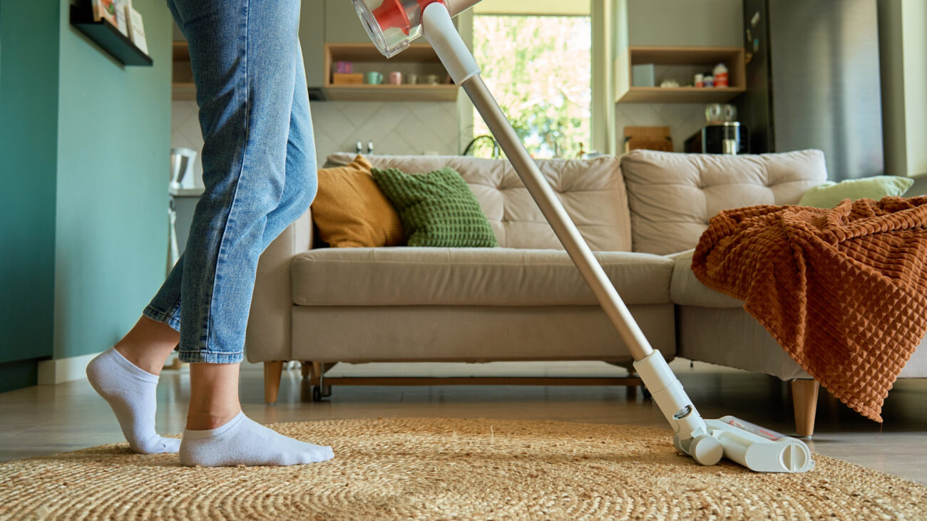Person vacuum cleaning floor rug