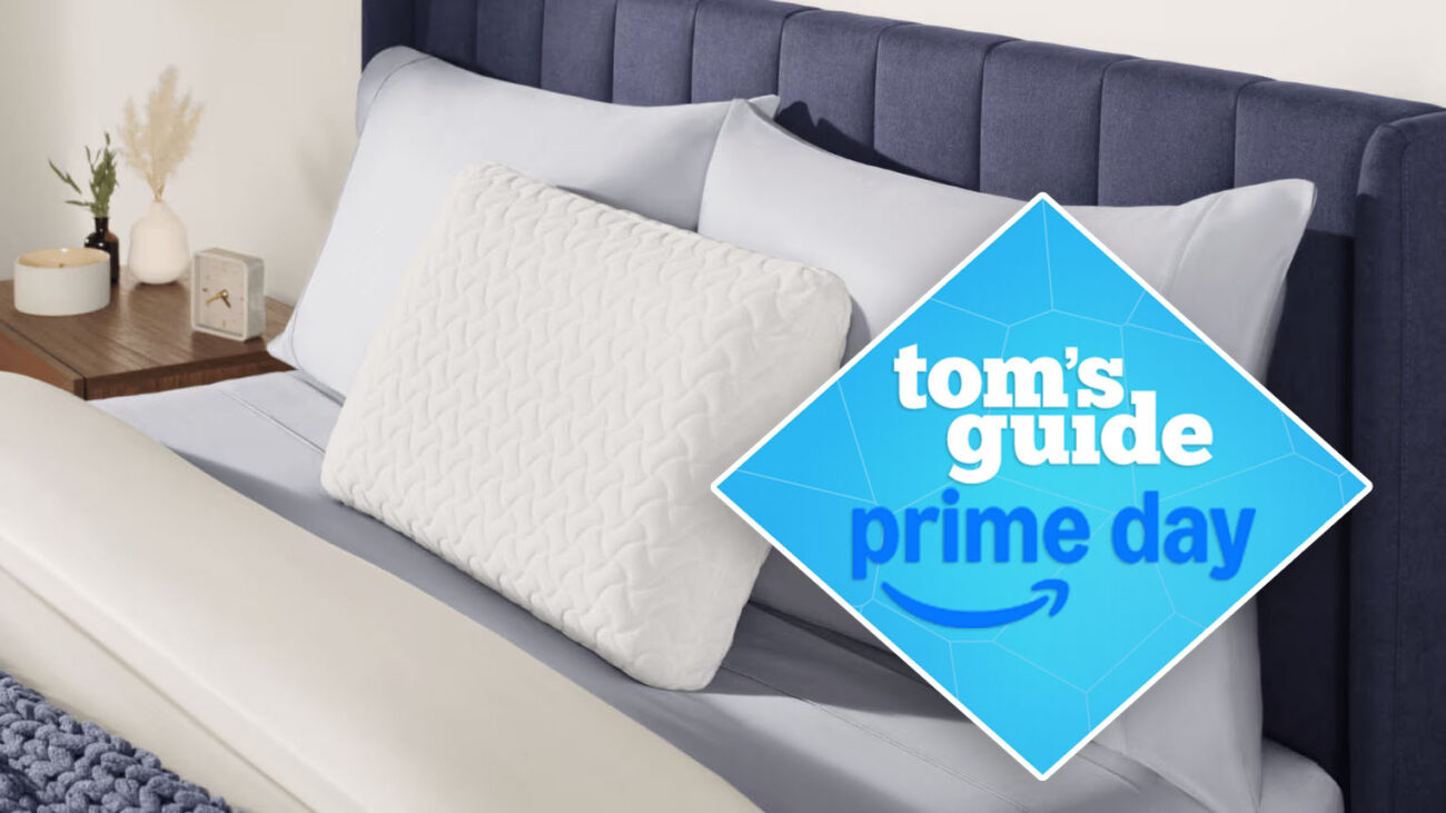 A close up of the head of a bed with three pillows resting against a headboard, the Tempur-Pedic Tempur-Cloud pillow is propped up in the front. A Tom's Guide Prime Day deals graphic to the right of the picture