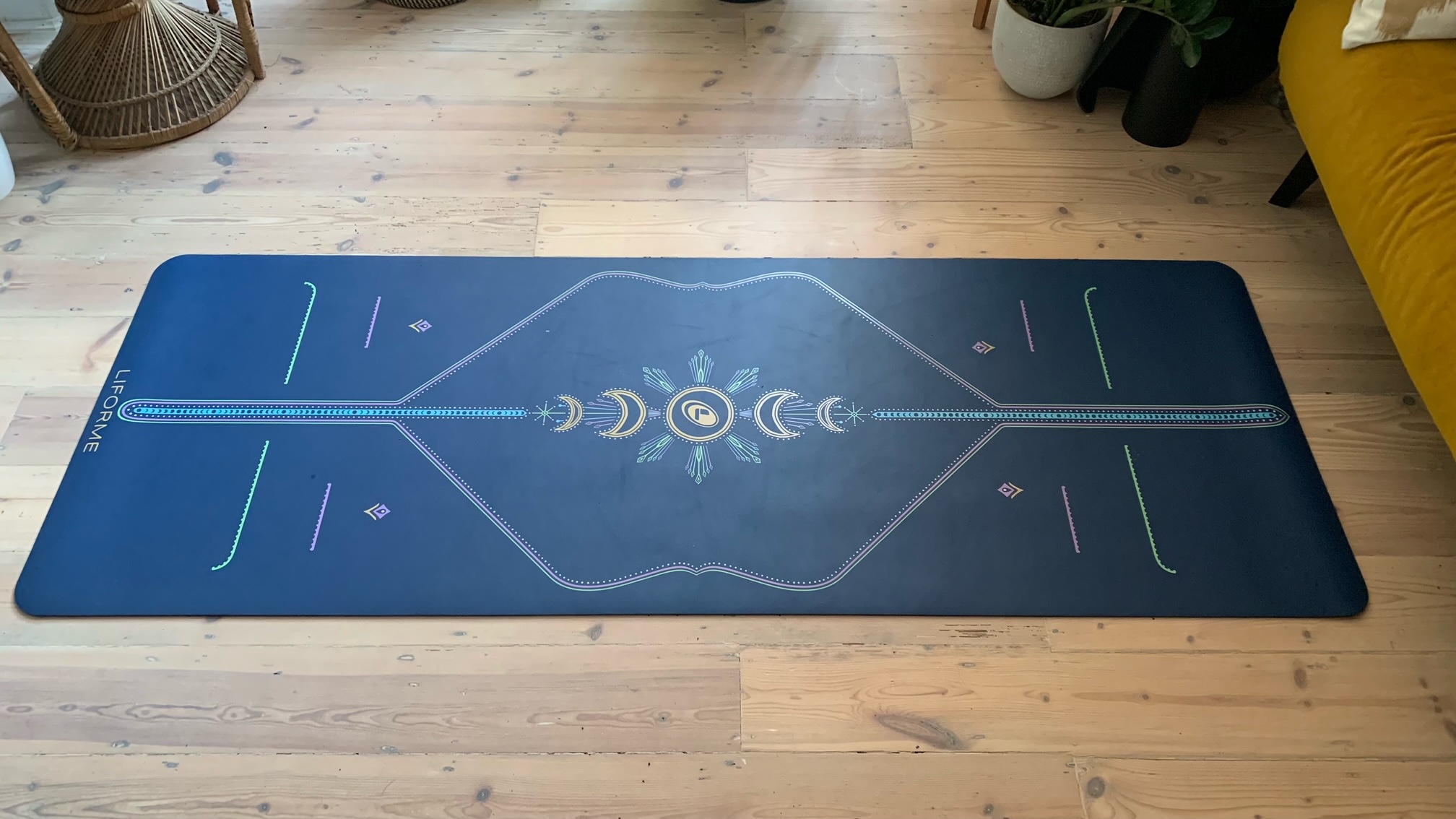 The Liforme Yoga Mat in blue rolled out on a wooden floor
