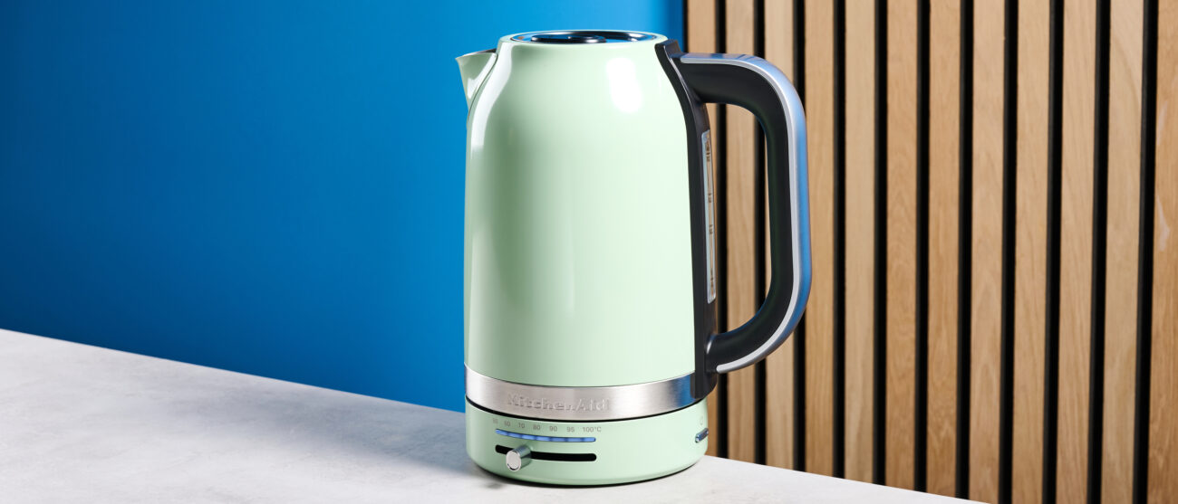 the kitchenaid 1.7L kettle in pistachio photographed on a white marble counter with a blue background