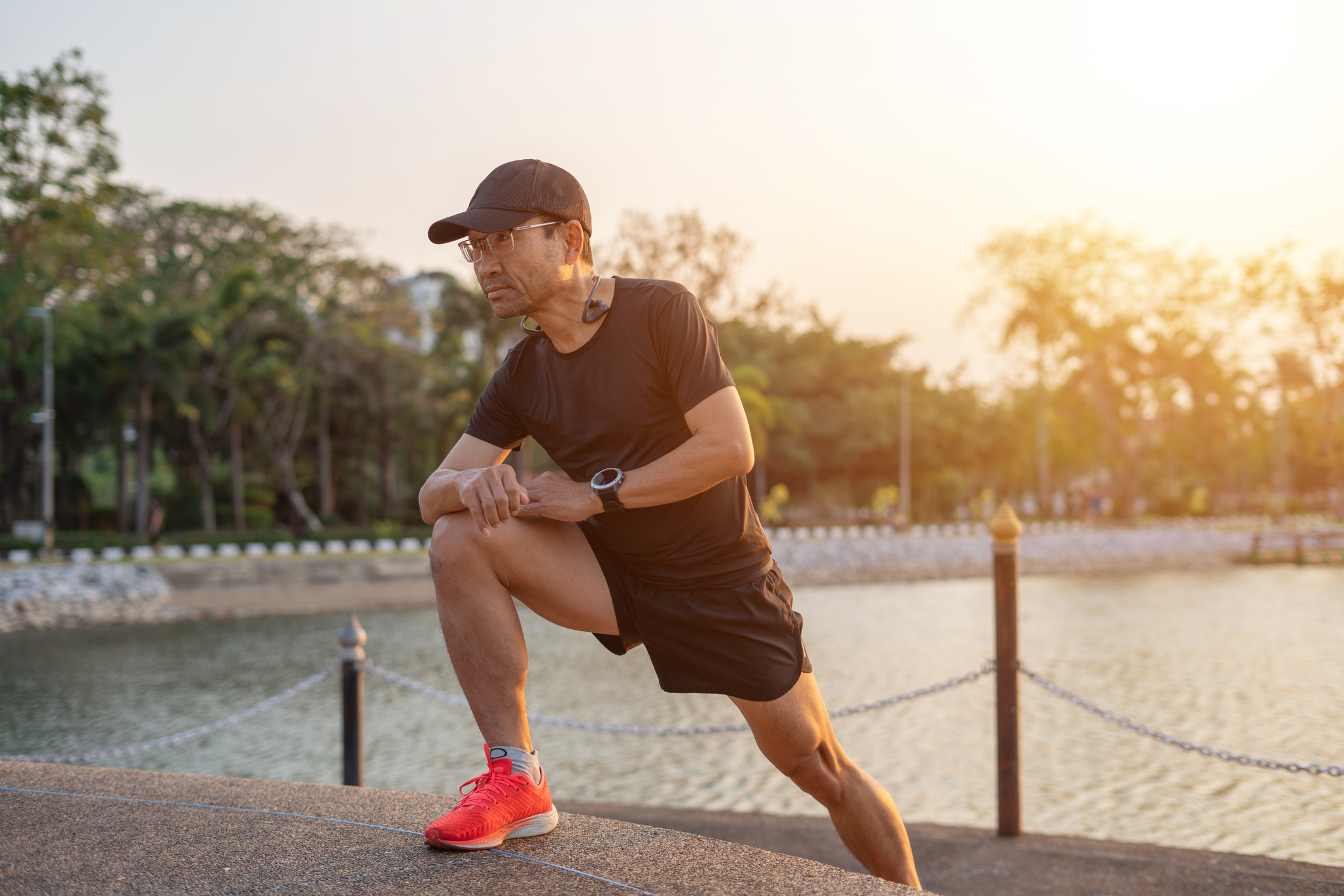 Man in running clothes stretches next to a lake
