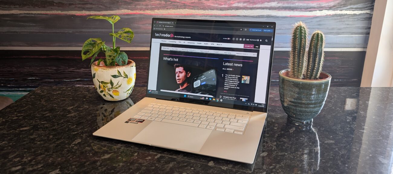 The Zenbook S 16 photographed on a dark marble surface with potted plants in the background.