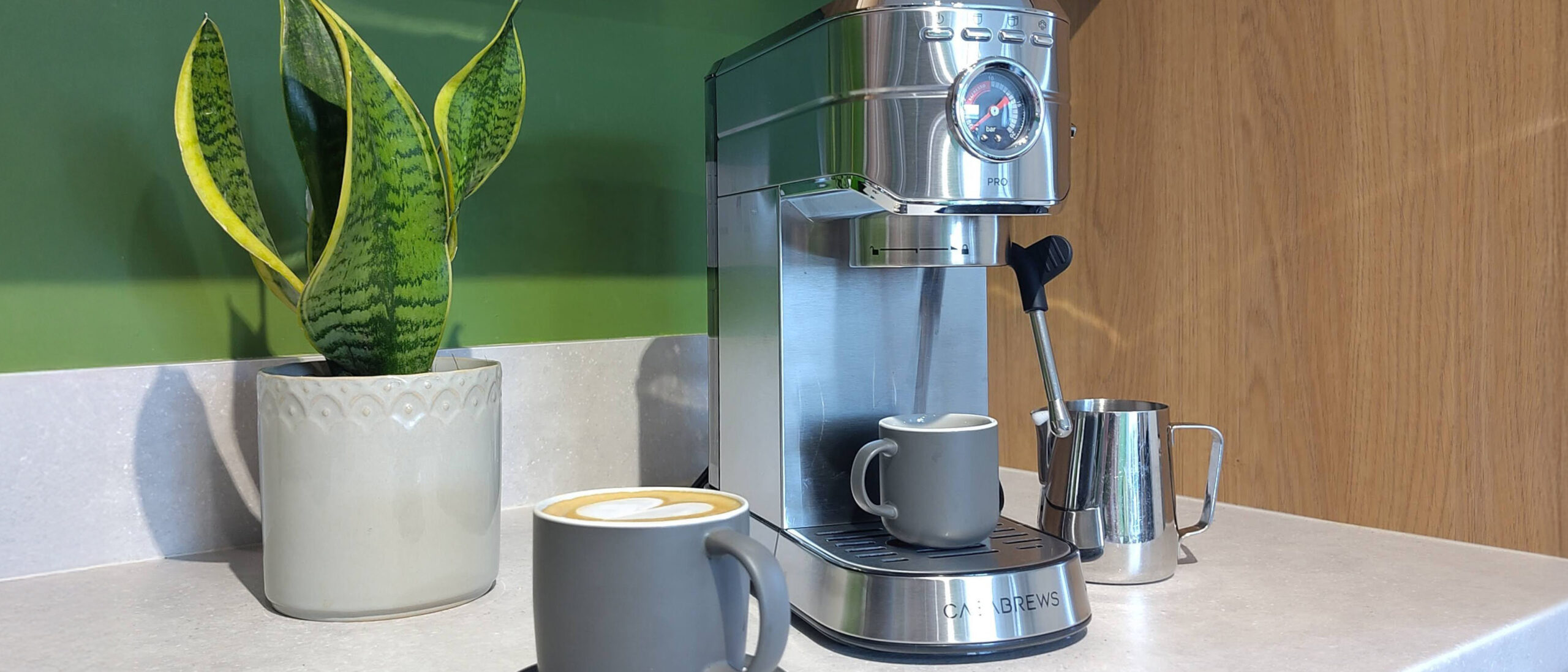 Casabrews 5418 Pro coffee maker on kitchen counter with coffee cups, milk pitcher, and plant