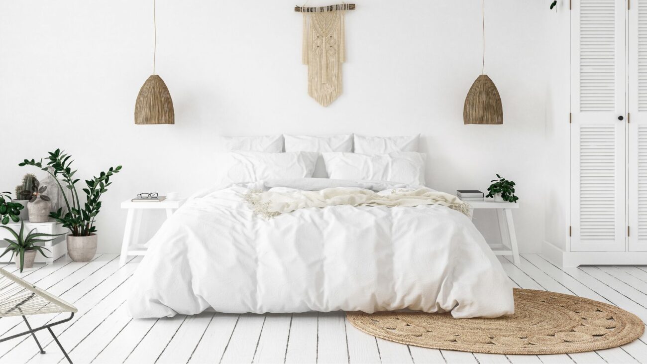 Image shows a scandi-style bedroom with a white comforter on a white wooden bedframe