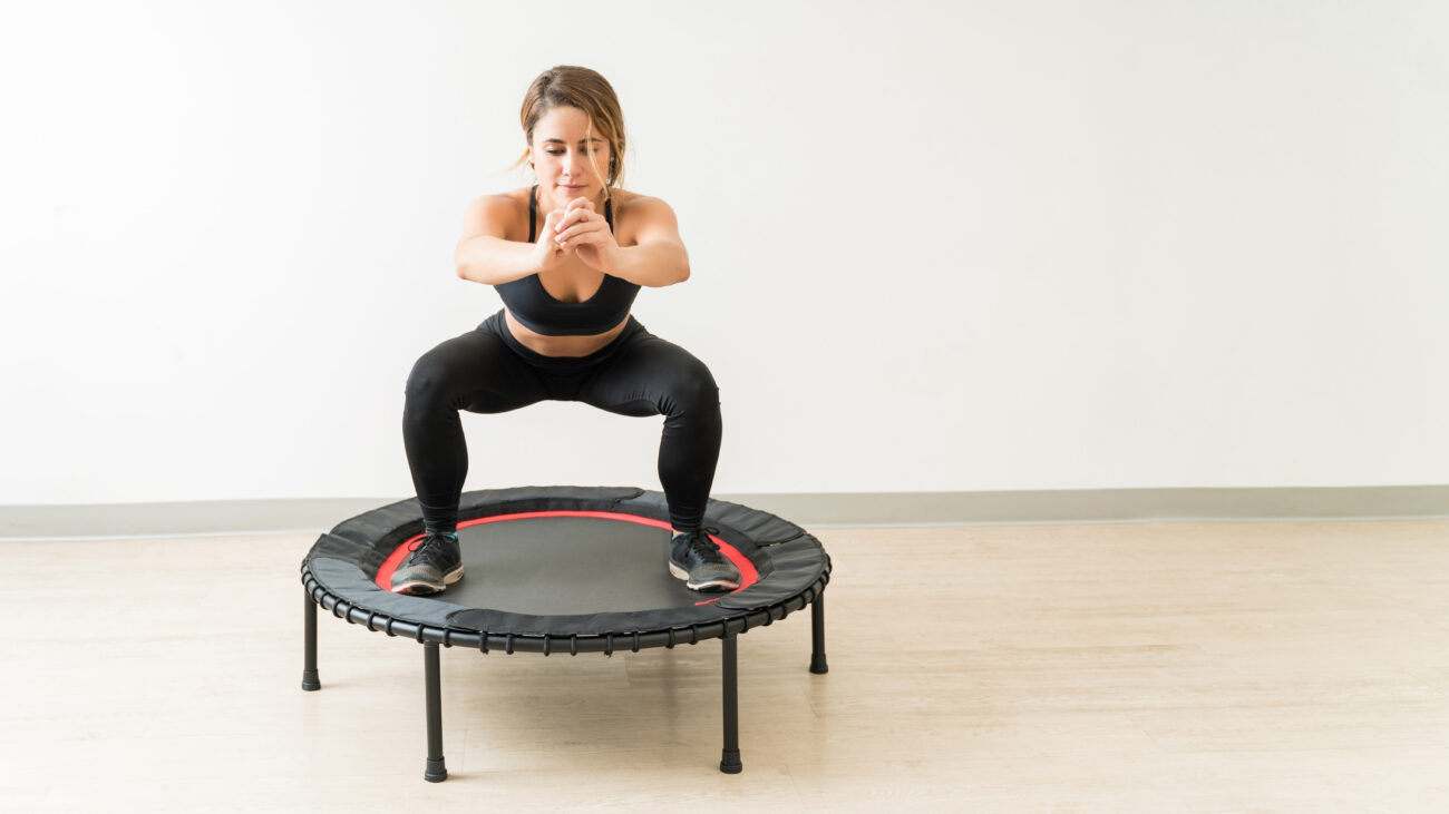 Woman performing a squat on mini trampoline in studio