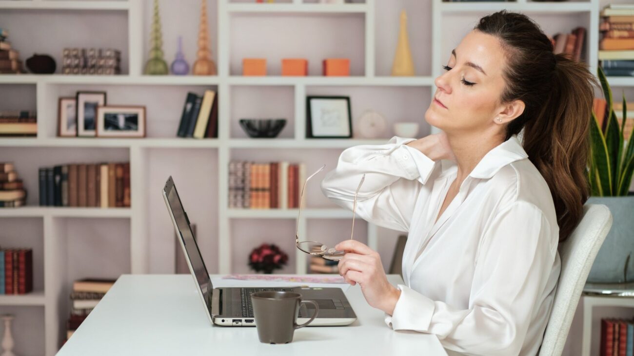 woman at desk hold neck in pain