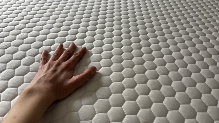 A hand feels the temperature of the Helix Premium Memory Foam Mattress Topper with GlacioTex.