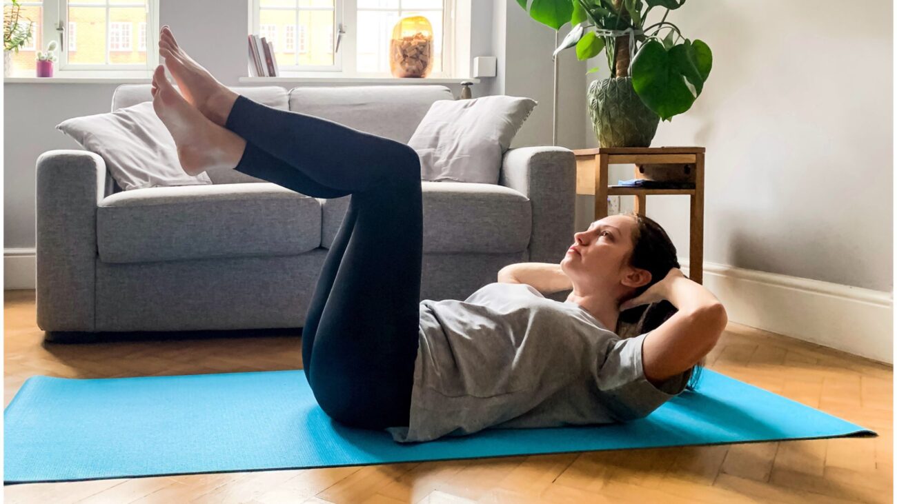 woman on yoga mat doing abs crunches