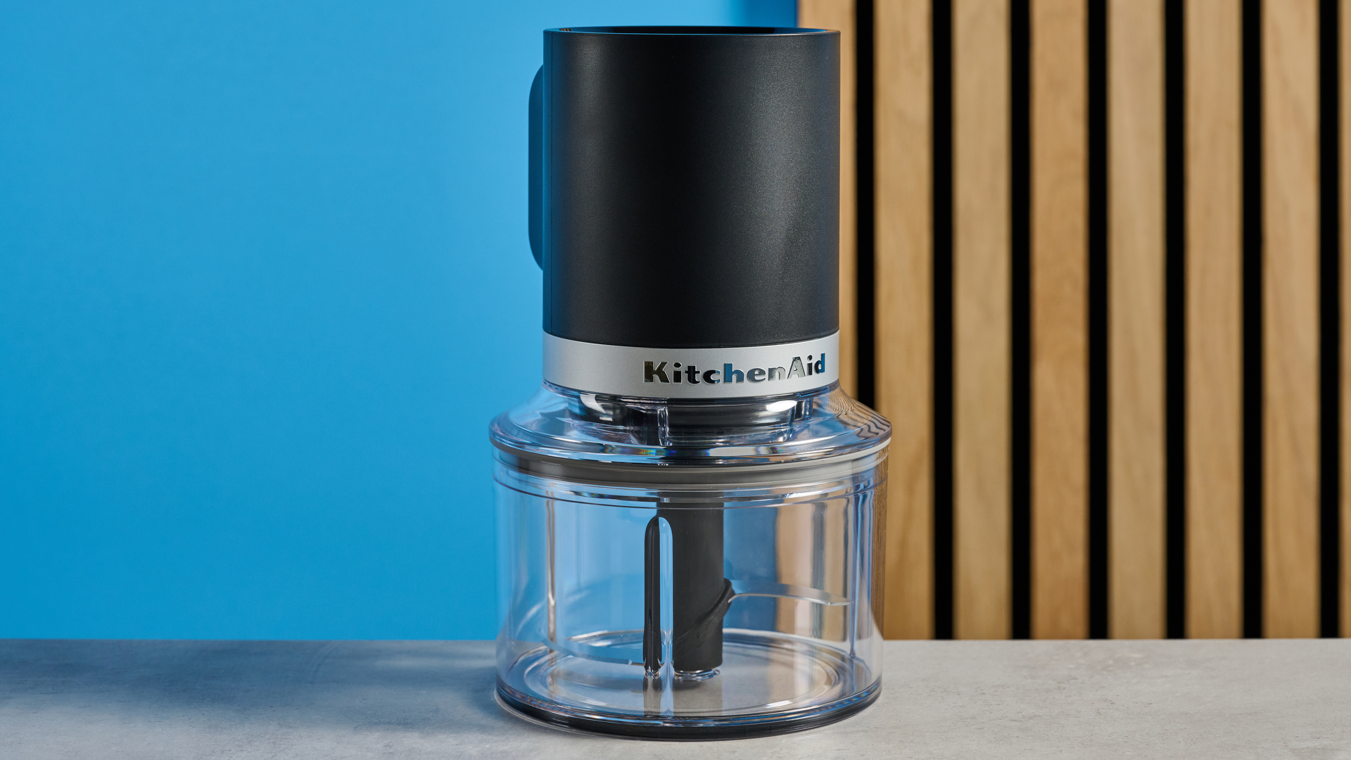 KitchenAid Cordless Top Down Food Chopper photographed in front of a blue background.