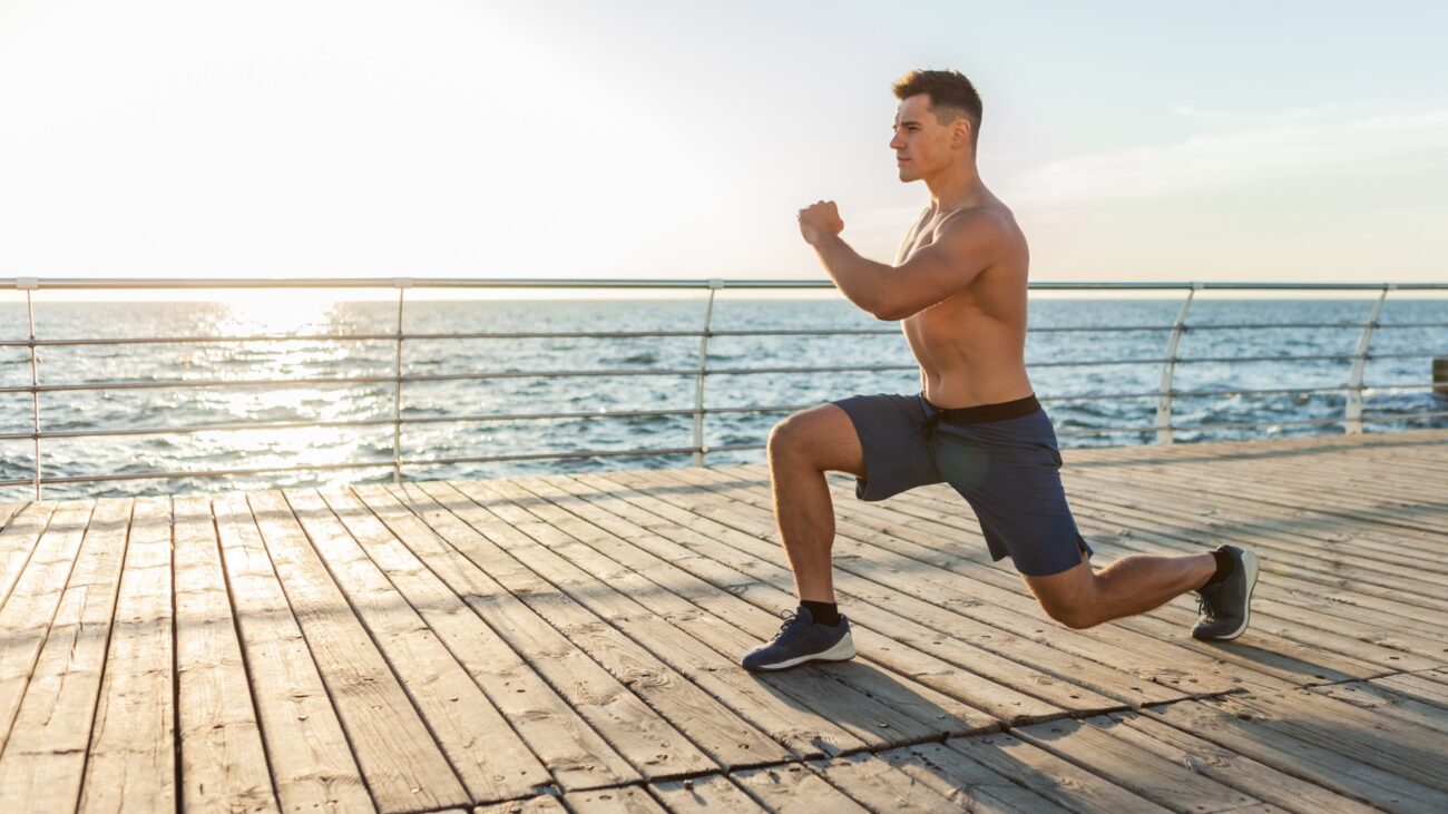 Man performing bodyweight lunges outdoors next to ocean