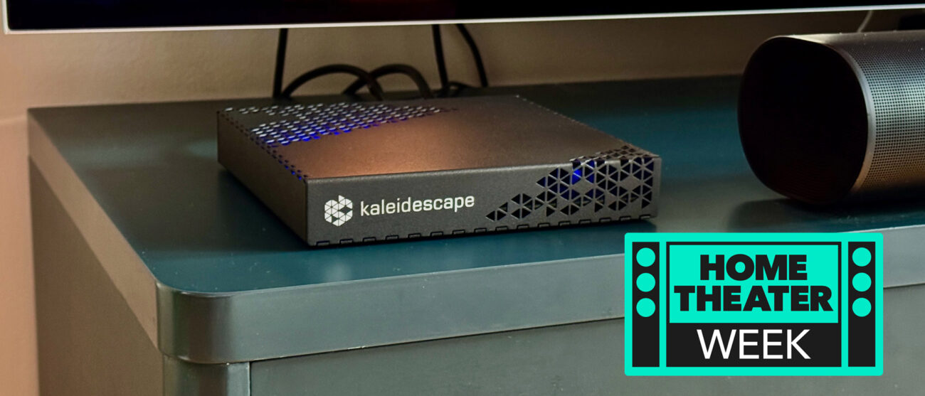 The Kaleidescape Strato E Movie Player on a navy blue TV unit. A badge saying "Home Theater Week" is in the bottom right corner.