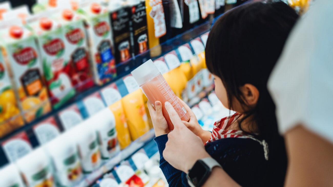 A little girl chooses a fruit drink with her parent. They are both reading the label